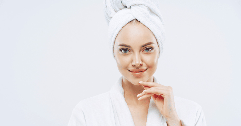 a lovely lady on a hair towel showing her lovely face by placing her left hand in her jawline