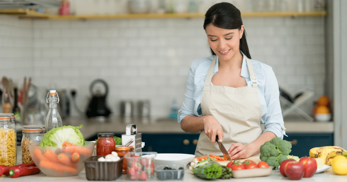 A woman looking happy and cooking healthy meal at home.