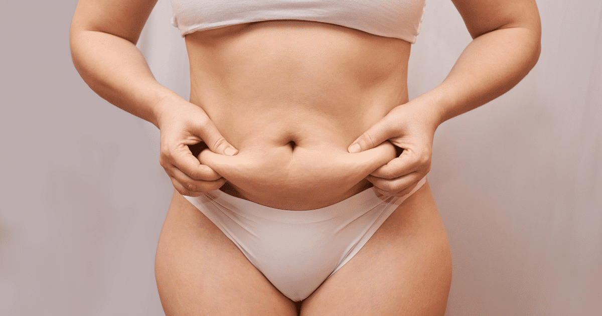 A woman poking her tummy fat.