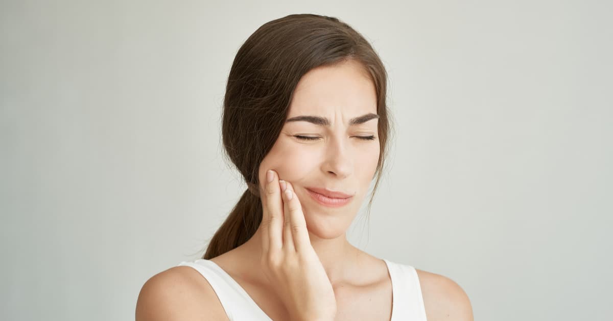 woman holding their jaw in pain