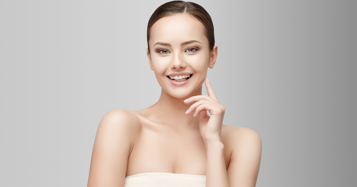 A woman with a clear, glowing skin and is wearing minimal makeup, emphasizing her natural beauty.